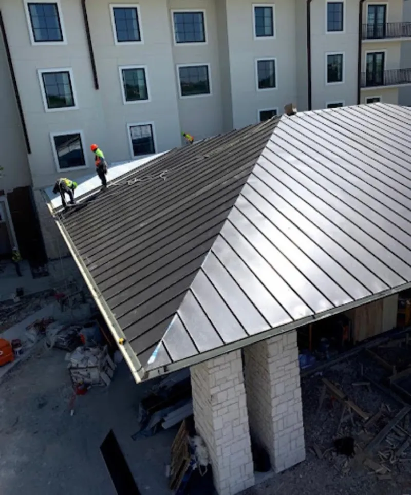 Crew installing standing seam metal roof panels on a commercial project in Weirton